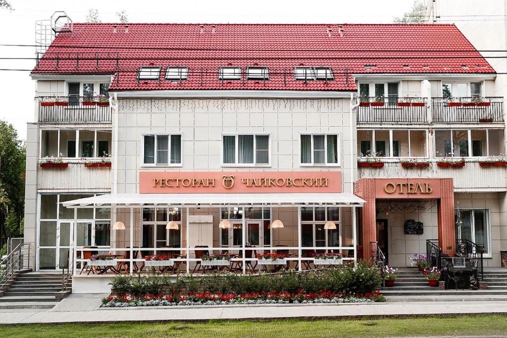 a white building with a red roof at Отель Чайковский in Chaykovskiy