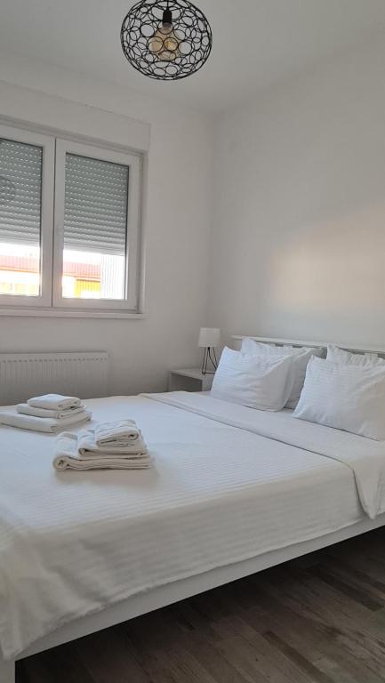 a white bed with two towels on top of it at Apartmani Iva in Banja Koviljača