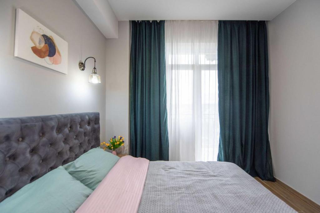 Schlafzimmer mit einem Bett mit grünen Vorhängen und einem Fenster in der Unterkunft Apart Hotel New Line in Tbilisi City