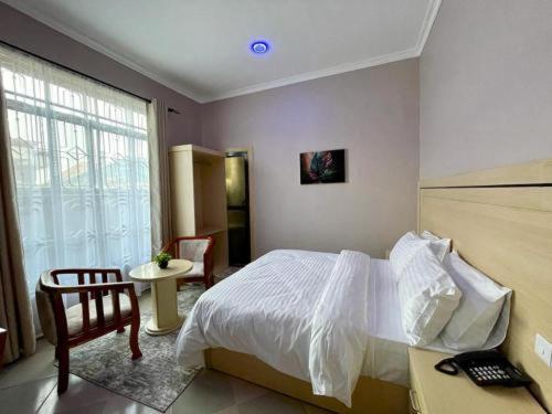 ein Schlafzimmer mit einem Bett, einem Stuhl und einem Fenster in der Unterkunft ROSA HOTEL AND APARTMENT - ILAZO in Dodoma