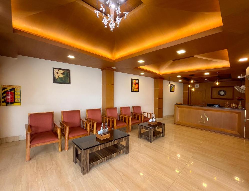 una sala de espera con sillas rojas y una mesa en Shree Residency en Erode