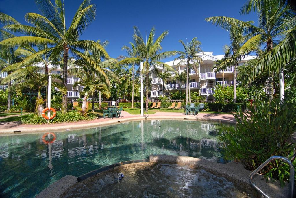 a swimming pool with palm trees in front of a building at Cairns Beach Resort in Cairns