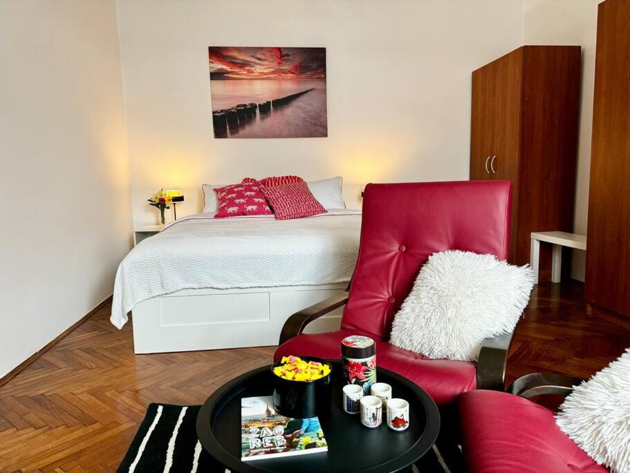 a living room with a bed and a red chair at Downtown Delight: Chic Oasis in Zagreb