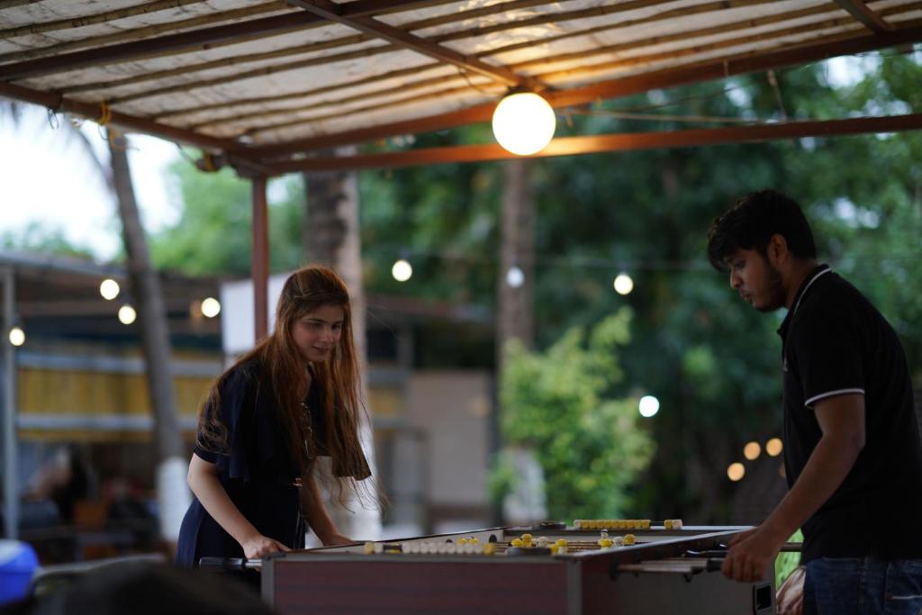 un hombre y una mujer jugando un juego en una mesa en Off The Grid Glamps en Khopoli