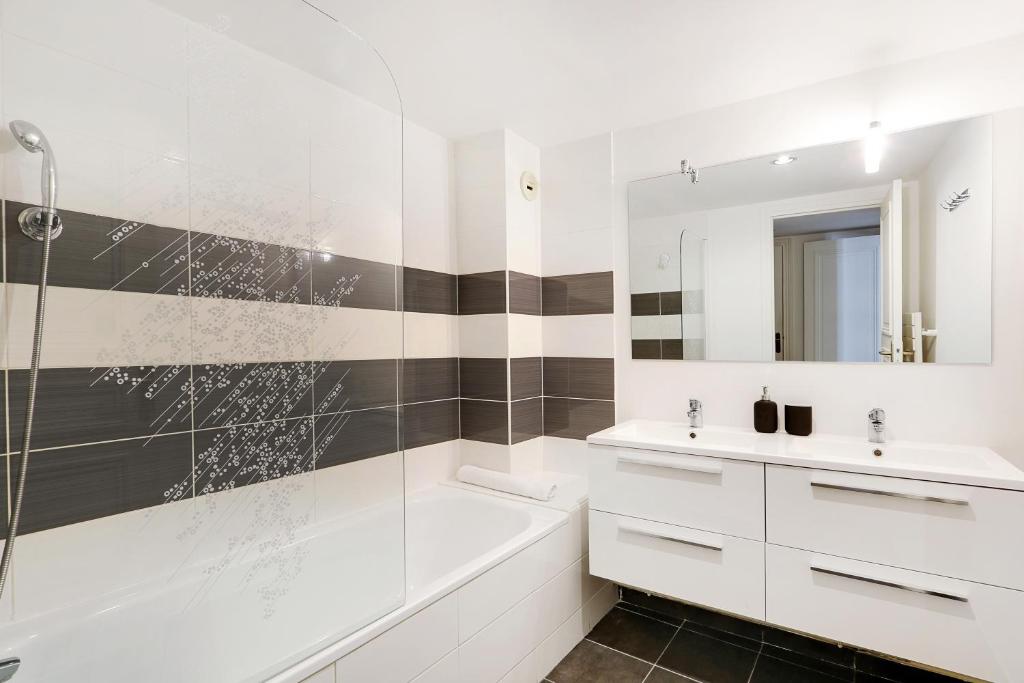 une salle de bain blanche avec une baignoire et un lavabo dans l'établissement Pick A Flat's Apartment in Champs-Elysées - Rue Ponthieu, à Paris