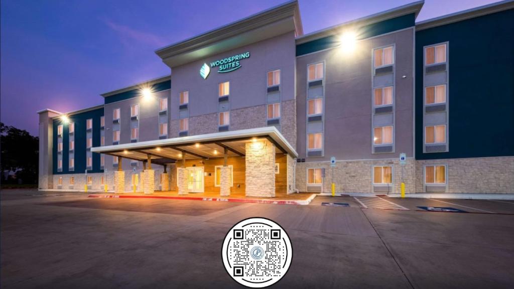 una rappresentazione di un hotel di notte con un cartello hotel di WoodSpring Suites Dallas Plano Central Legacy Drive a Plano