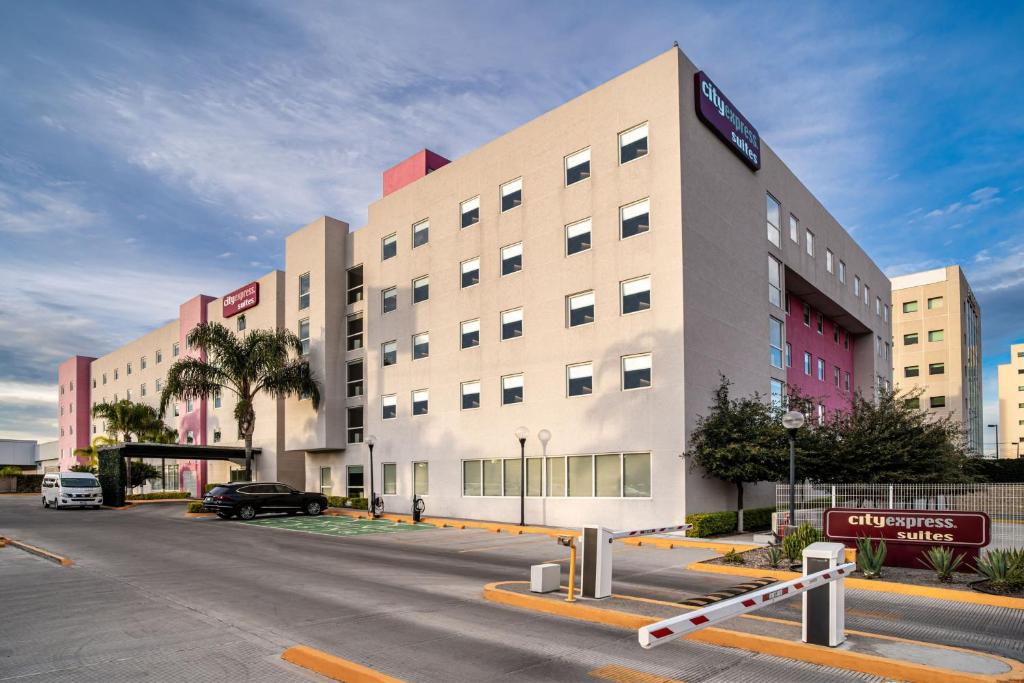 un gran edificio con un estacionamiento delante de él en City Express Suites by Marriott Queretaro en Querétaro