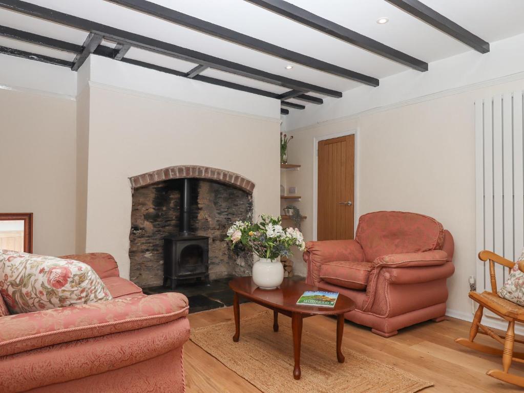 a living room with two chairs and a fireplace at Glebe Cottage in Yelverton