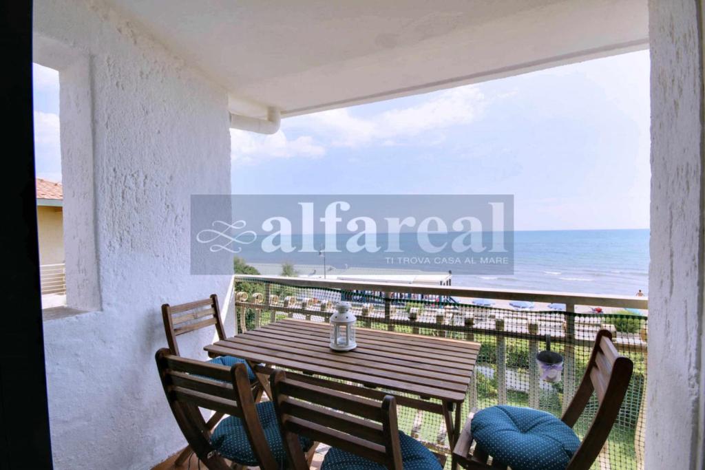 un tavolo in legno con sedie su un balcone con vista sull'oceano di Rosanna sul mare a Castiglione della Pescaia