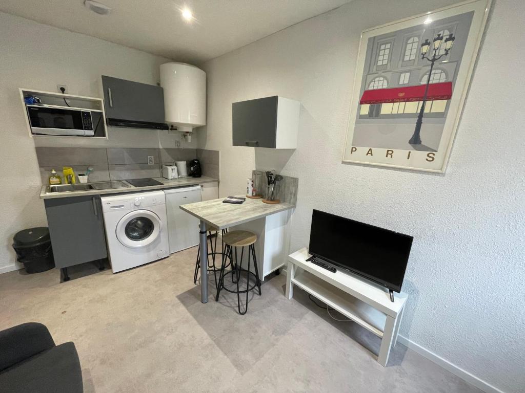 a small kitchen with a table and a tv in it at APPARTEMENT HYPER CENTRE numéro 101 in Roanne