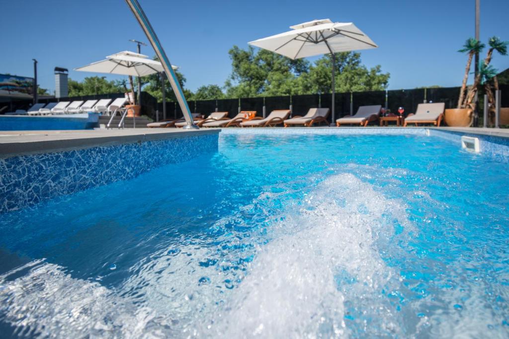 - une piscine d'eau avec des chaises et des parasols dans l'établissement Luxury Apartment & Rooms, à Ljubuški
