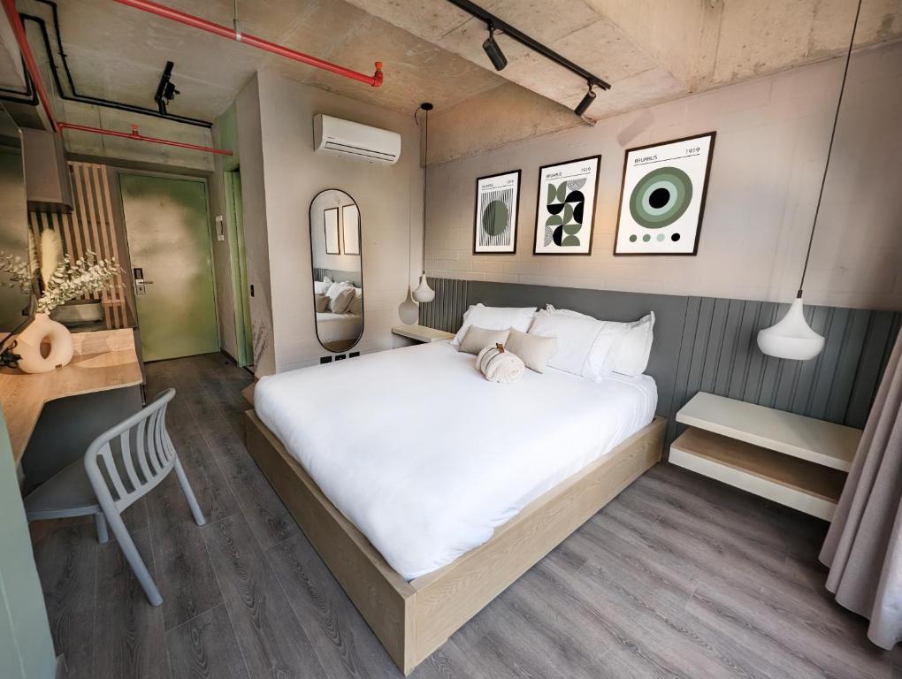 1 dormitorio con 1 cama blanca grande y escritorio en Urbit Social Lofts, en Medellín