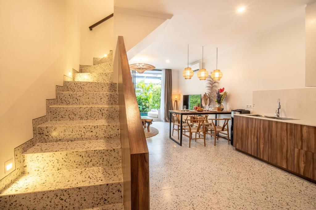 a staircase in a house with a kitchen and a dining room at Sunny Village Berawa in Canggu