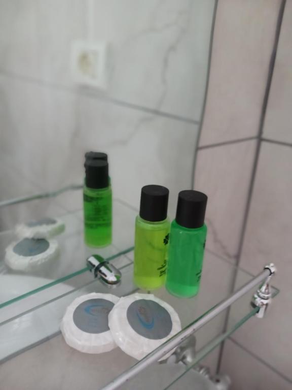 two green bottles sitting on a glass shelf in a bathroom at Vangert Apartment in Berat
