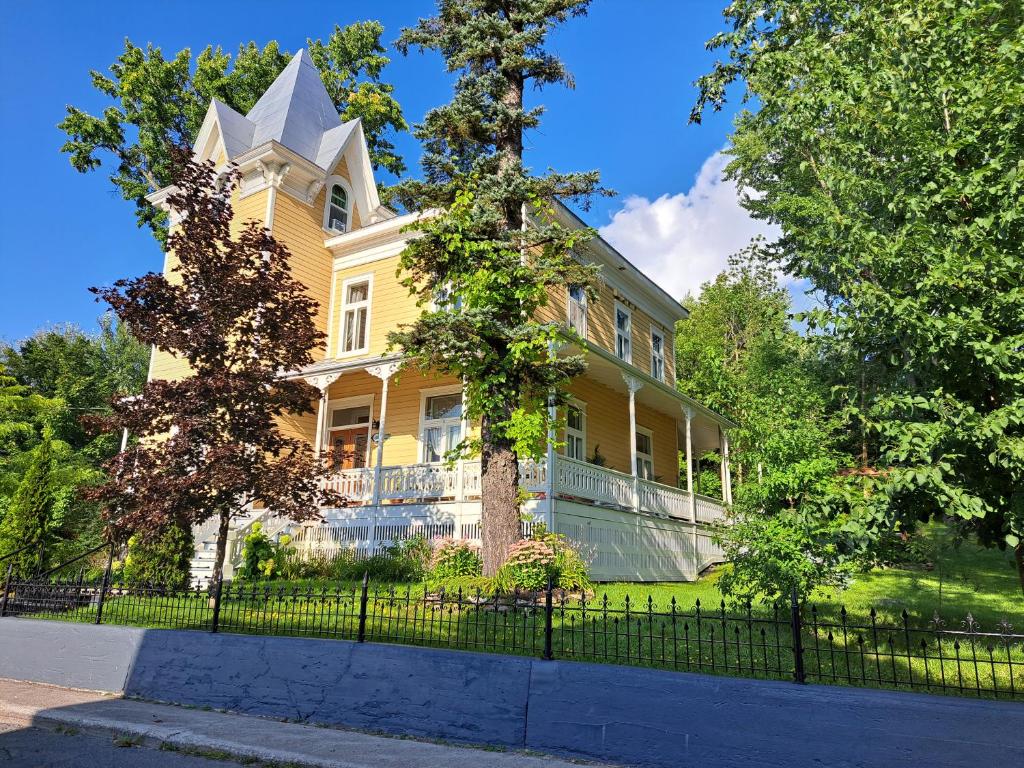 una gran casa amarilla con una valla delante en Gîte au Charme Victorien en Beauceville