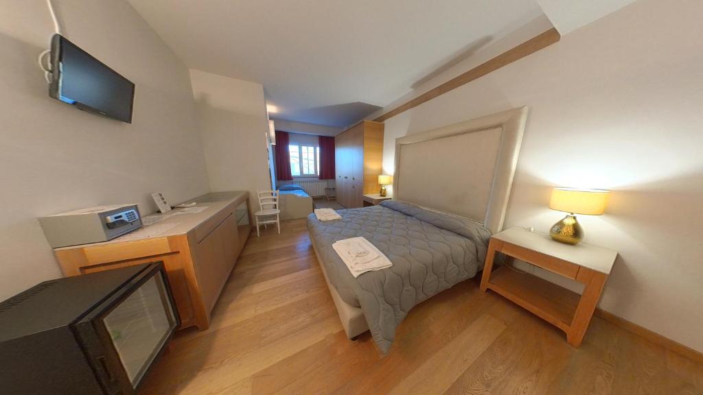 una camera da letto con un letto, una scrivania e una televisione di San Cataldo Hotel a Faggiano
