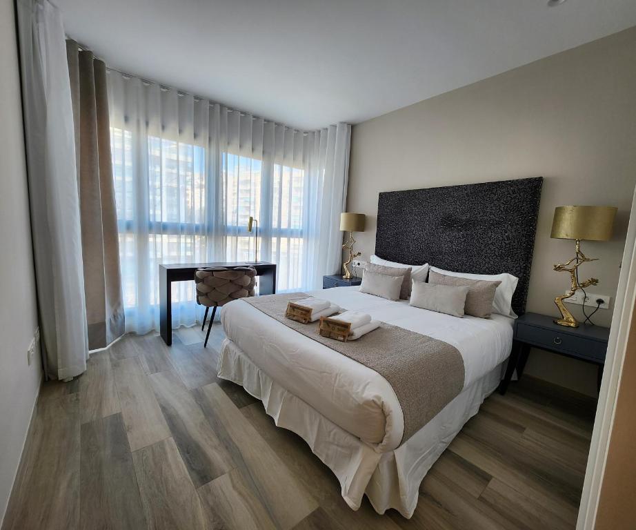 a bedroom with a large white bed and a desk at Pont de Fusta Apartments in Valencia