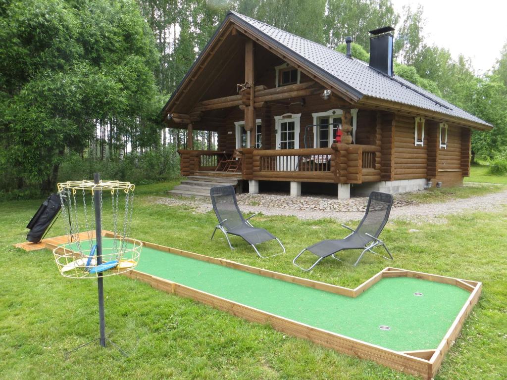 une petite cabane en rondins avec un pied de golf en face de celle-ci dans l'établissement Cottage-karaoke Koivikko, à Äänekoski