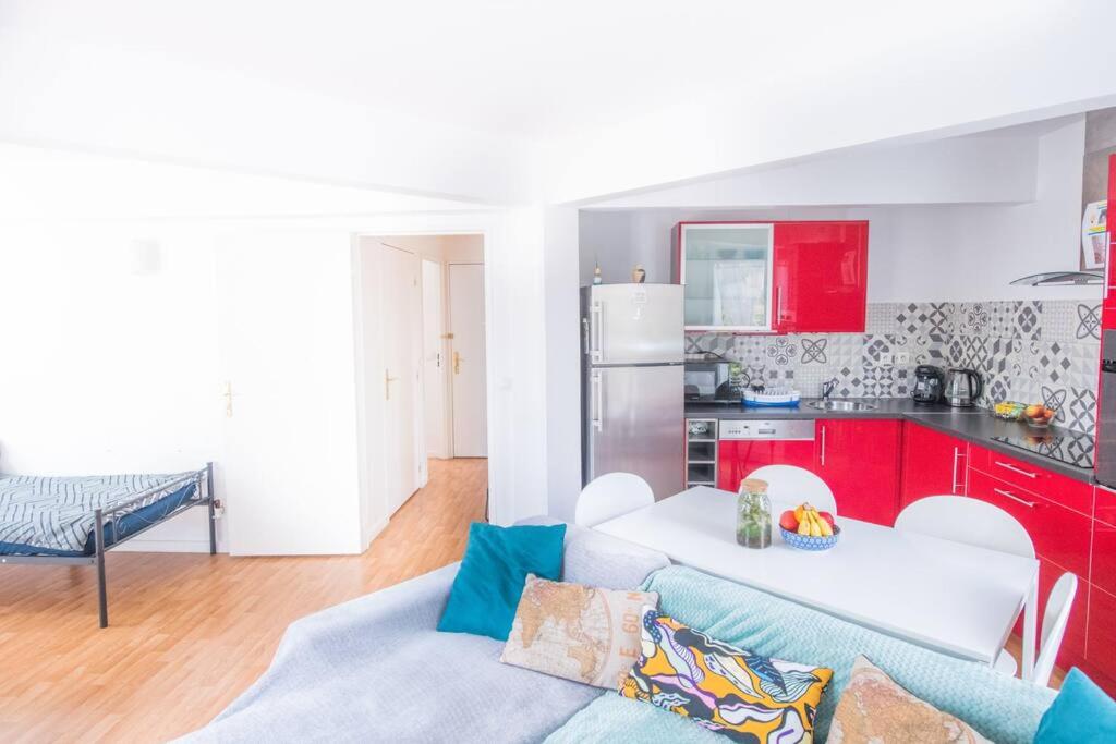 un salon avec un canapé et une cuisine avec des placards rouges dans l'établissement Superbe Appartement près du Stade de France et Paris, à Villetaneuse