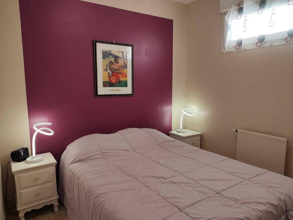 sypialnia z łóżkiem i fioletową ścianą w obiekcie Appartement VUE MER EXCEPTIONNELLE plage du Coz-Pors à TREGASTEL - Ref 721 w mieście Trégastel