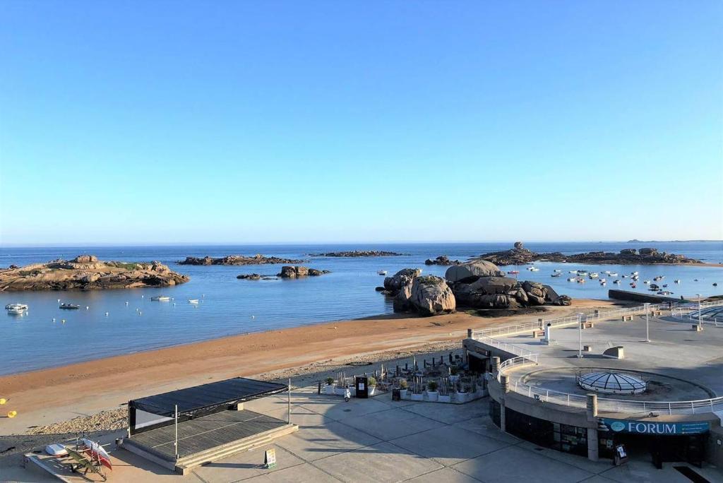 widok na plażę z łodziami w wodzie w obiekcie Appartement VUE MER EXCEPTIONNELLE plage du Coz-Pors à TREGASTEL - Ref 721 w mieście Trégastel