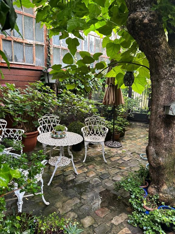 d'une terrasse avec une table et des chaises sous un arbre. dans l'établissement cosy loft in town house, à Paris