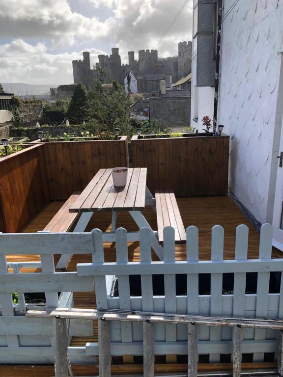 a wooden bench sitting on a balcony with a table at Compton House 1 in Conwy