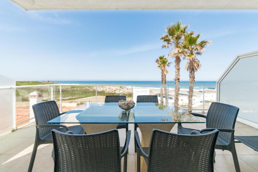 a dining room with a table and chairs and the beach at By the Beach in Praia d'el Rey in Óbidos