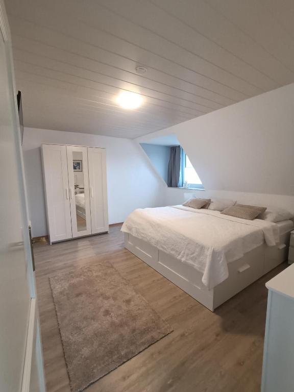 a white bedroom with a bed and a mirror at LütjeFöhr in Alkersum