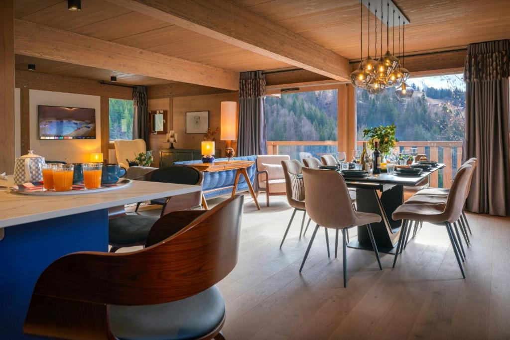 ein Esszimmer mit Tischen und Stühlen und einem großen Fenster in der Unterkunft Chalet Ours Rouge - OVO Network in Le Grand-Bornand