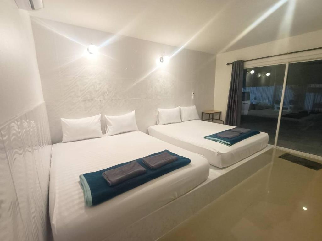 2 Betten in einem kleinen Zimmer mit Fenster in der Unterkunft Saan Rak Resort in Prachuap Khiri Khan