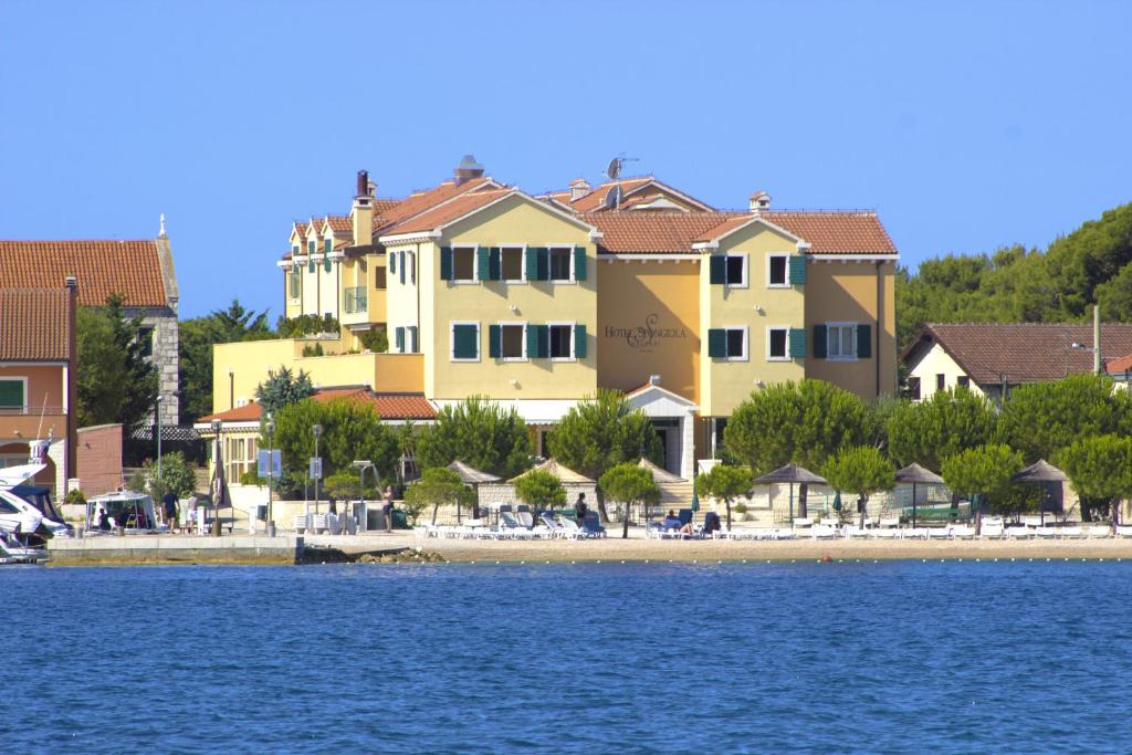 a group of houses on a beach next to the water at Hotel Spongiola in Krapanj