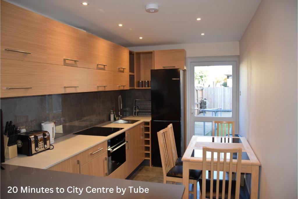 a kitchen with a black refrigerator and a table at Four Bedroom House Chandos Road in London