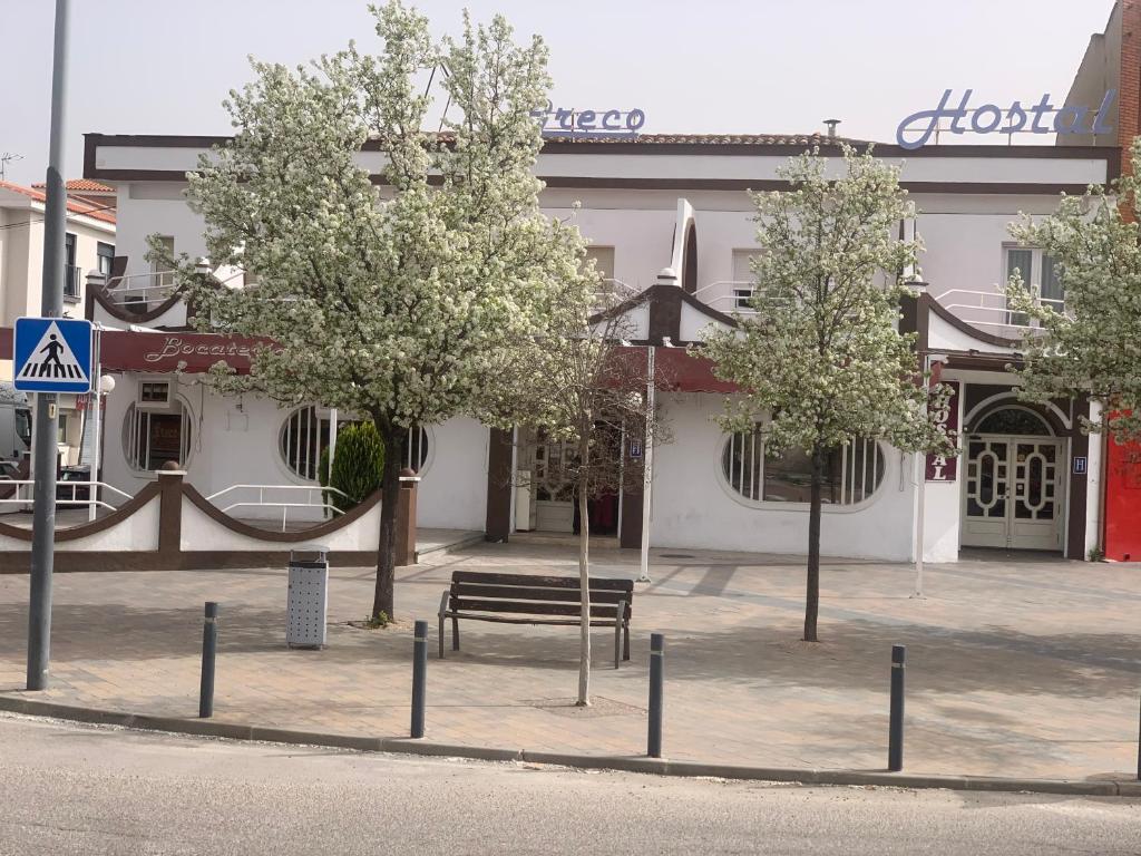 a building with a bench and trees in front of it at HOSTAL-CAFE GUTGRECO in Sonseca