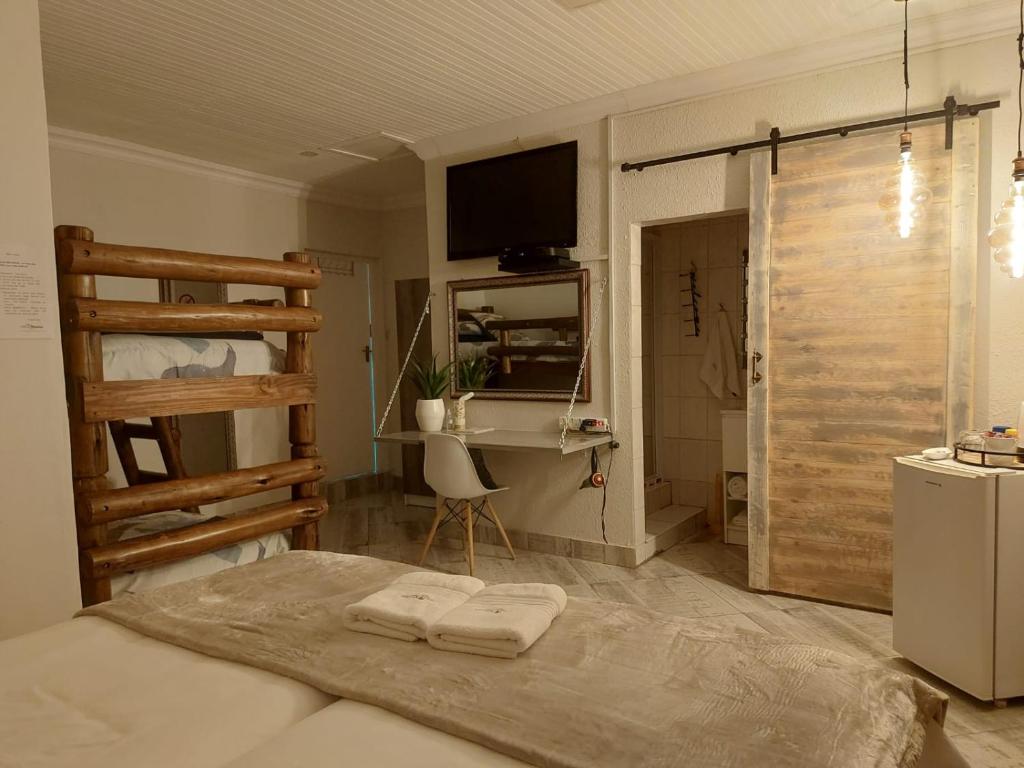 Villa Mariss Guesthouse في Kraaifontein: غرفة نوم بسرير ومكتب وتلفزيون