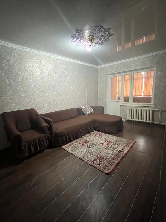 uma sala de estar com um sofá castanho e um tapete em Квартира em Shymkent