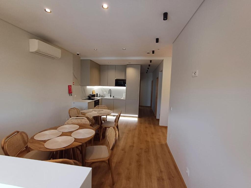 una habitación con mesas y sillas y una cocina en OPORTO Suites en Moreira