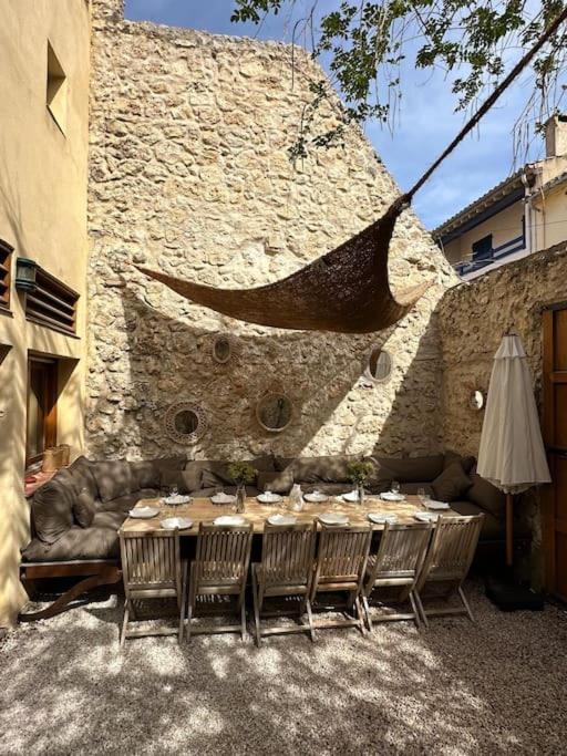 une table avec des chaises et un canapé en face d'un mur en pierre dans l'établissement Grande Maison familiale Leucate Village, à Leucate