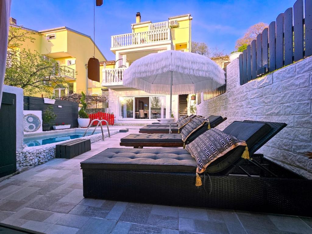 eine Terrasse mit 4 Betten mit einem Sonnenschirm und einem Pool in der Unterkunft Casa Memory in Crikvenica
