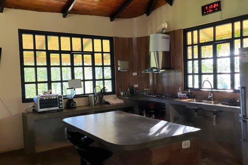 a kitchen with a table and a sink and windows at Casa de campo - Fundo El Alisal in Cajamarca