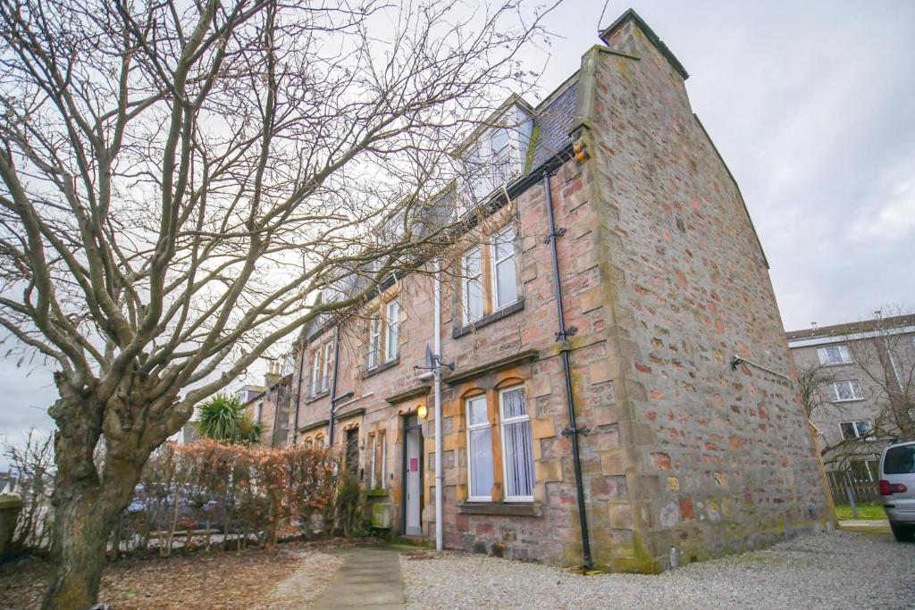 an old brick building with a tree in front of it at Telford Rd 5 Bedroom House Inverness in Inverness