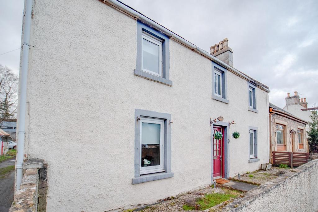 ein weißes Haus mit einer roten Tür in der Unterkunft Novar 4 Bedroom House Alness in Inverness