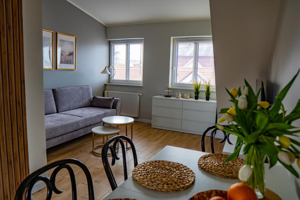 uma sala de estar com um sofá, uma mesa e cadeiras em Apartament Nr 2 Zaułek Portowy em Ustka