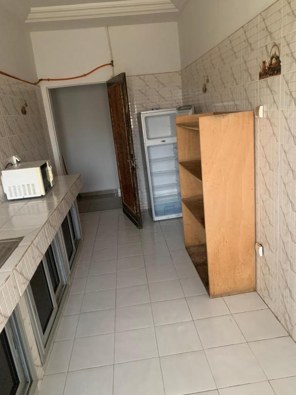 a small kitchen with a refrigerator and a tiled floor at Appartement chambre meublée 1 in Dakar