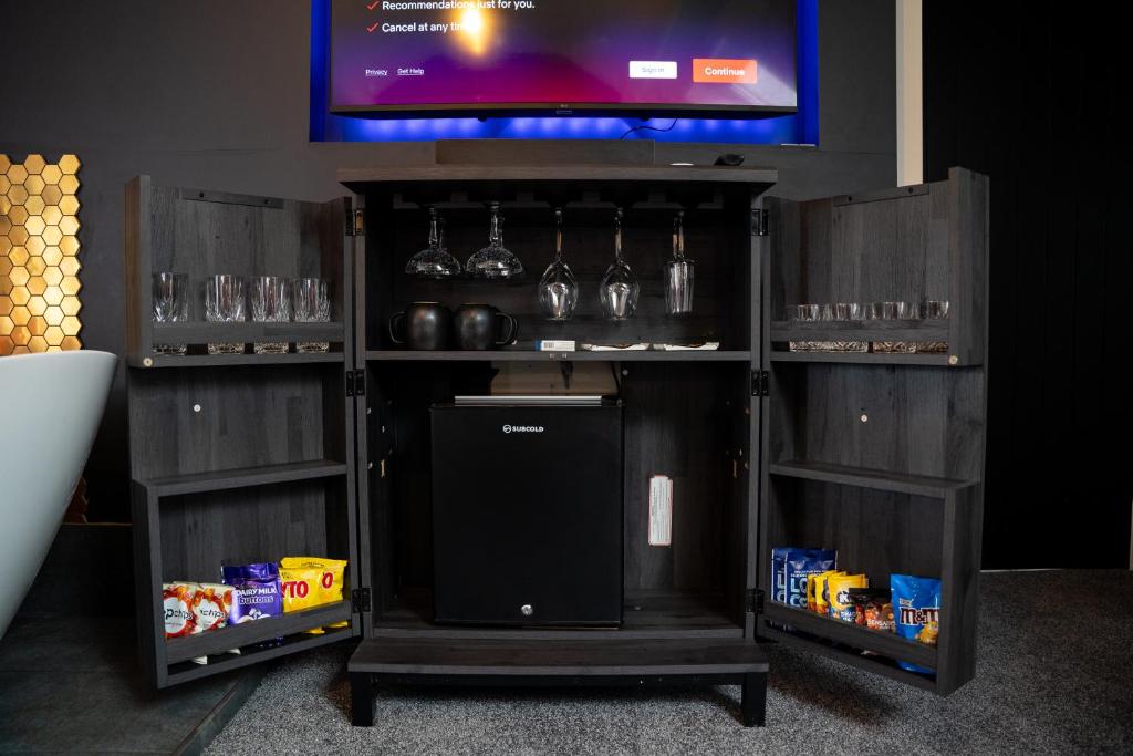 a bar with wine glasses and a tv on a wall at The Briers Country House in Newcastle