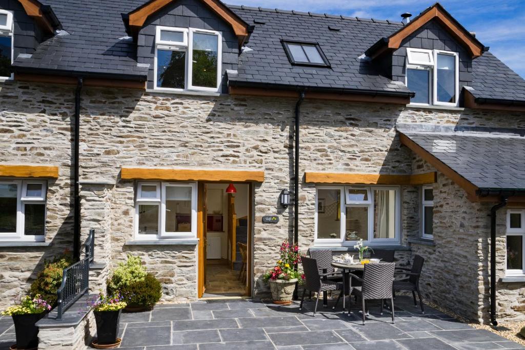 a stone house with a patio in front of it at Teifi Cottage Cenarth in Cenarth