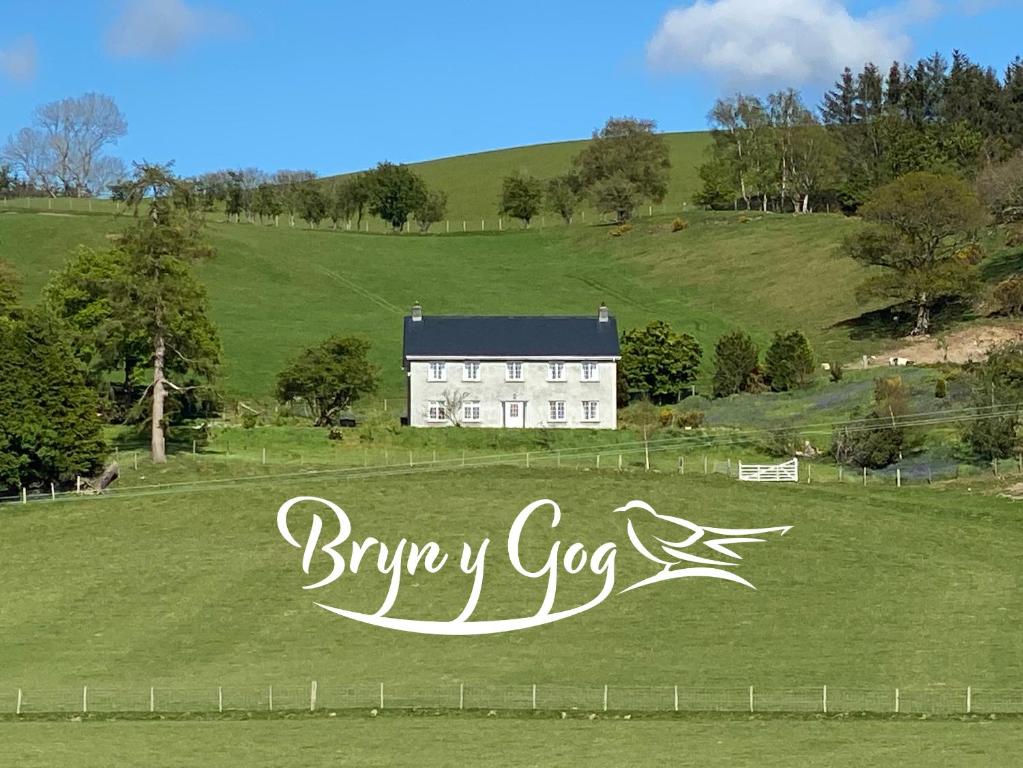 una casa blanca en un campo verde con un cartel en Bryn Y Gog Tregaron en Tregaron