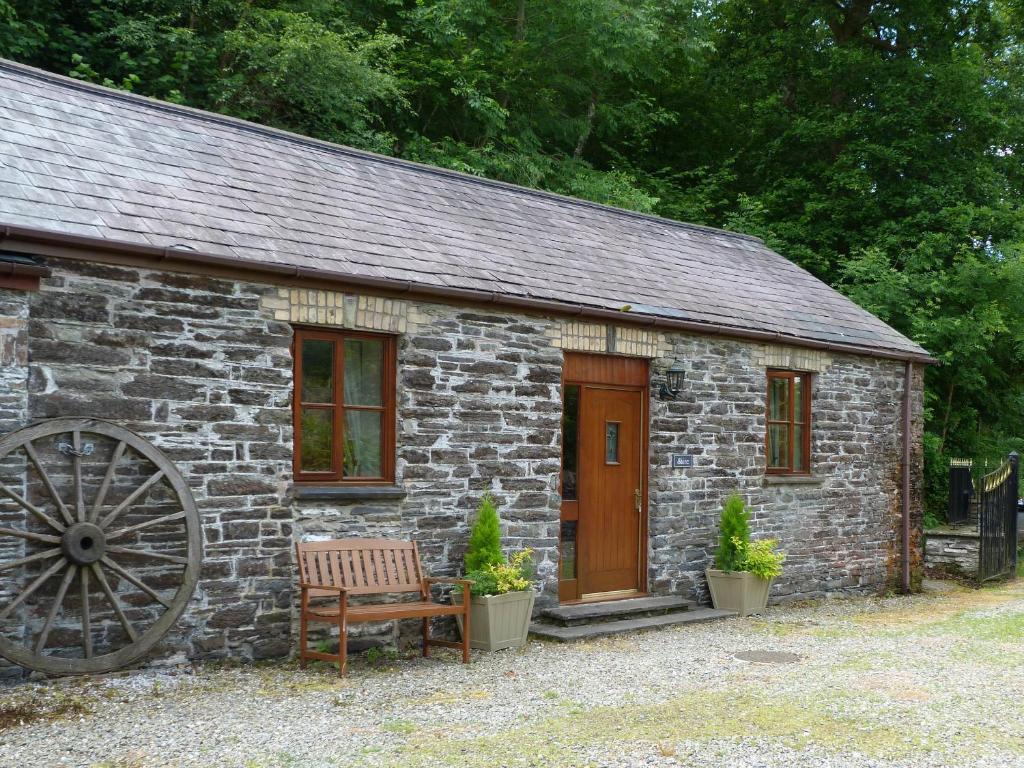 a stone cabin with a bench and a wooden door at Shire Cottage Devils Bridge in Yspytty Cynfyn
