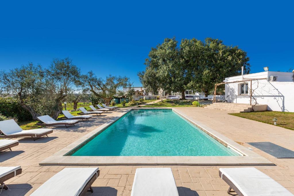 a swimming pool with chaise lounge chairs and a resort at Agriturismo Masseria Carrone in Carovigno