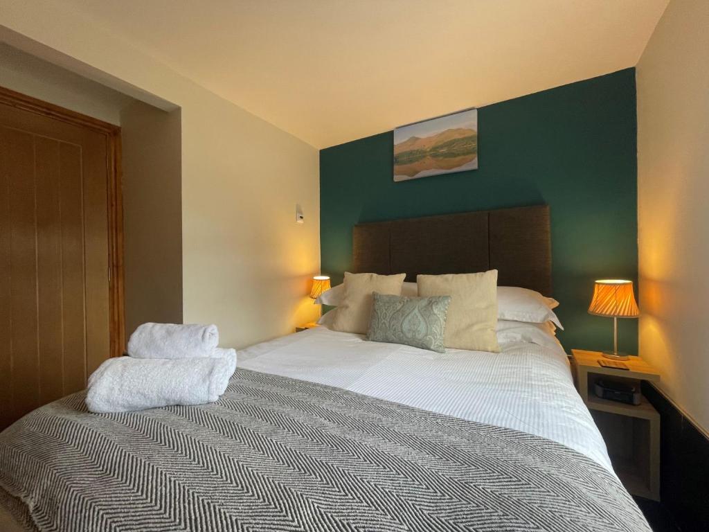 - une chambre avec un grand lit blanc et un mur vert dans l'établissement Tithe Cottage, à Keswick